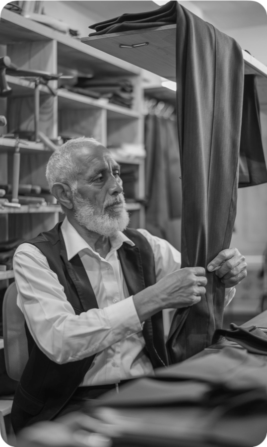 An older tailor inspecting a garment