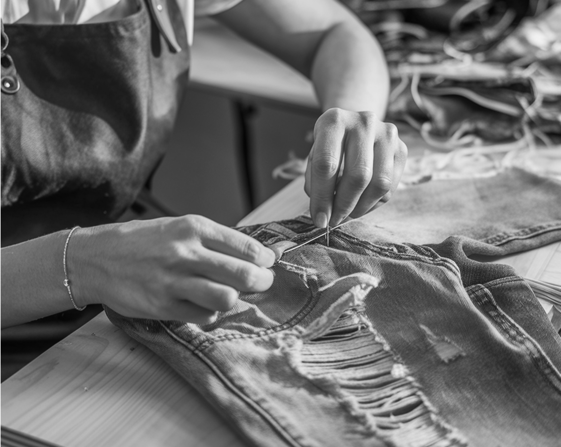 Hands stitching a tear in a pair of jeans
